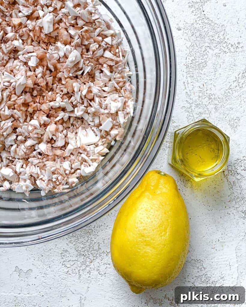 A bowl of finely chopped mushroom stems next to a lemon and a bottle of olive oil, ready to be sautéed for the stuffing.