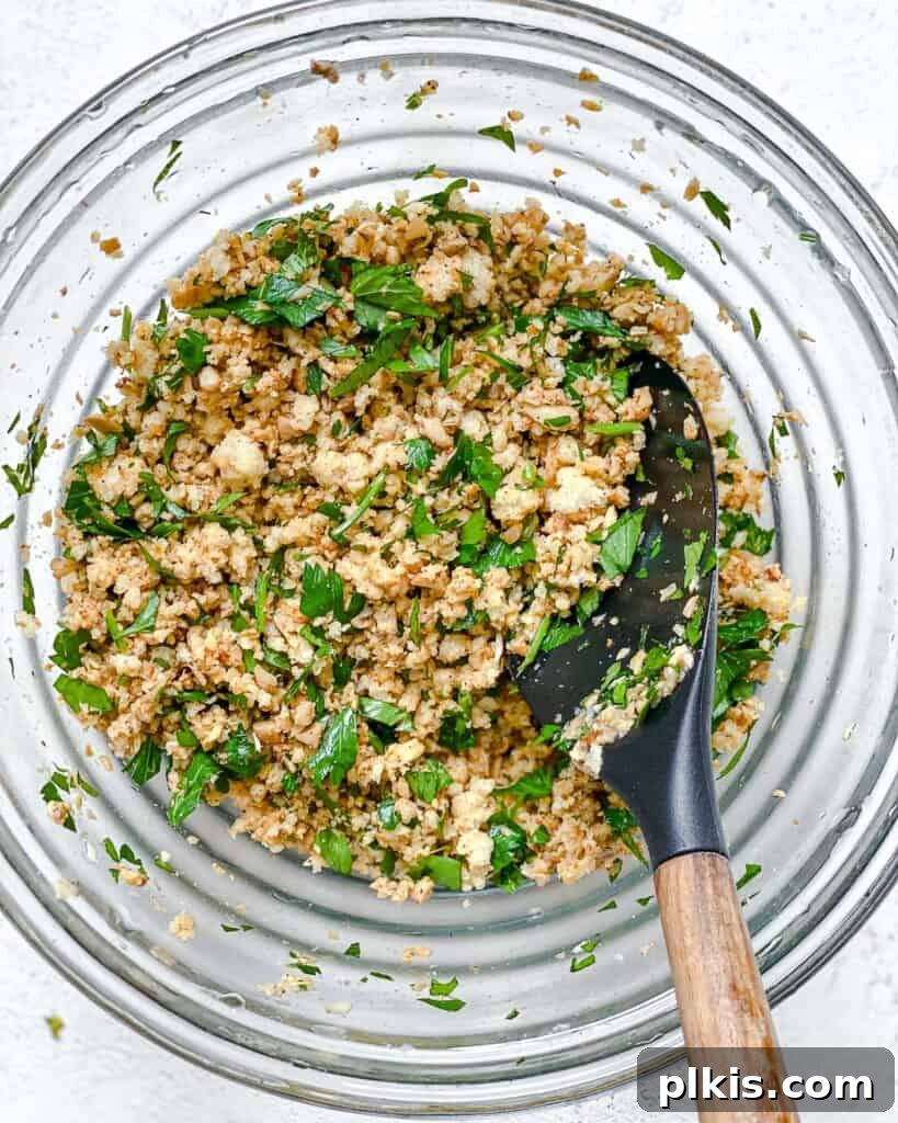 Process shot of combining sautéed mushroom stems and parsley with hydrated breadcrumbs in a mixing bowl for the stuffing.