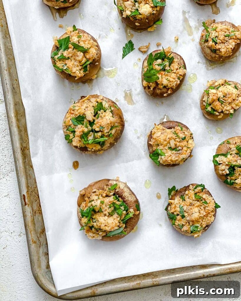 Mushroom caps on a baking dish, now generously filled with the savory breadcrumb mixture, ready for final baking.
