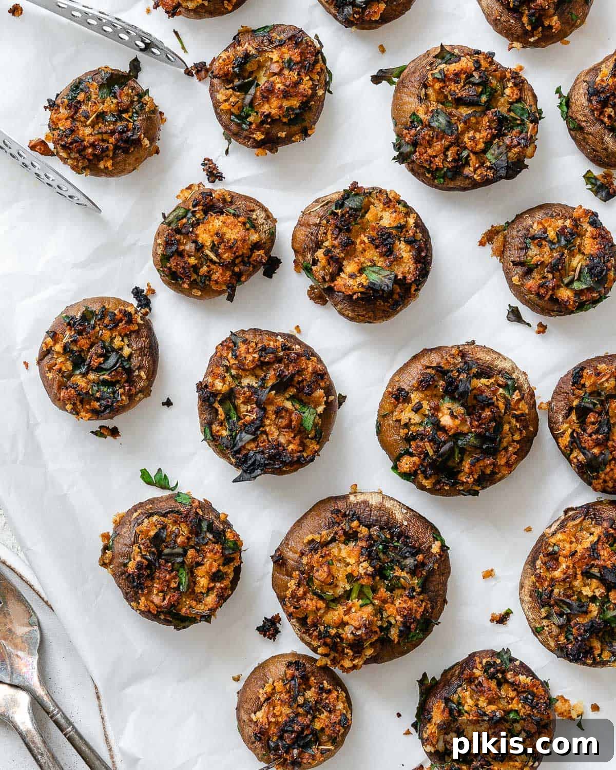 A close-up of fully cooked and golden Easy Vegan Stuffed Mushrooms on a white plate, showcasing their inviting texture and rich filling.