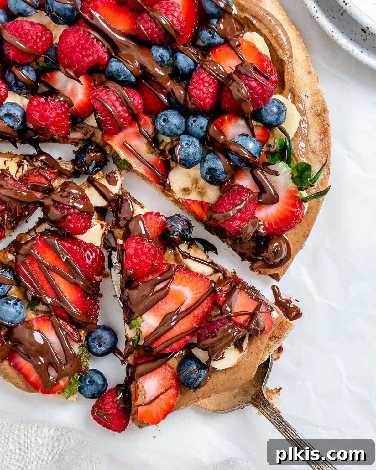 Sunshine Fruit Pizza 2 completed fruit pizza with one slice slightly shifted against a white background