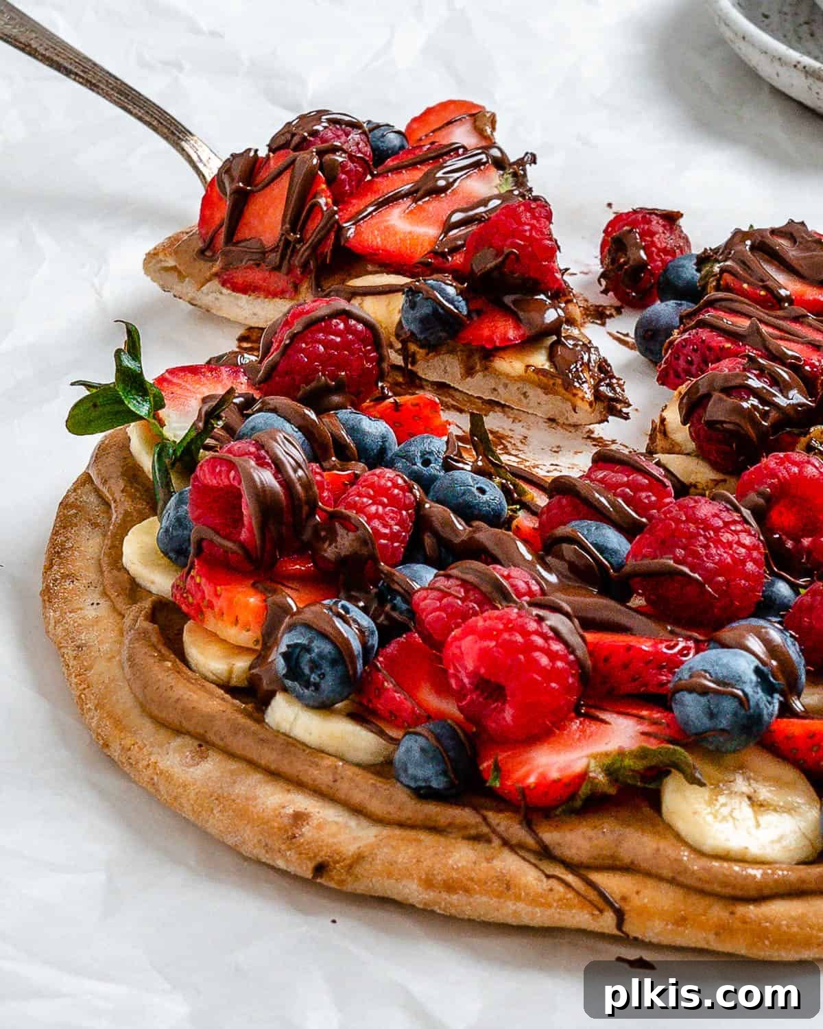 Sunshine Fruit Pizza 14 completed fruit pizza with one slice slightly shifted against a white background