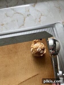 Crispy Vegan No-Bake Chocolate Peanut Butter Bites 6 process of putting a scoop of Peanut Butter Bon Bon on a silicone mat
