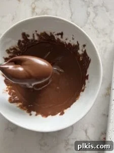 Crispy Vegan No-Bake Chocolate Peanut Butter Bites 7 process of melting chocolate in a small white bowl against a white marble surface