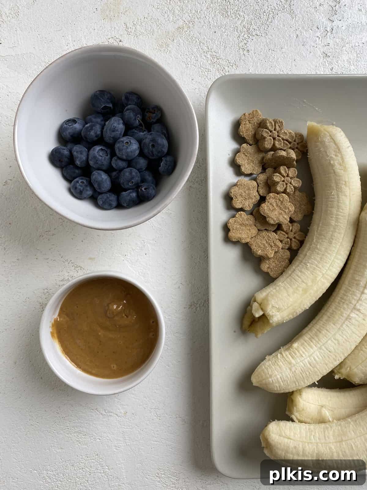Frosty Peanut Butter Banana Puppy Snacks 4 All the fresh and natural ingredients needed for Frozen Peanut Butter Banana Dog Treats laid out on a white surface