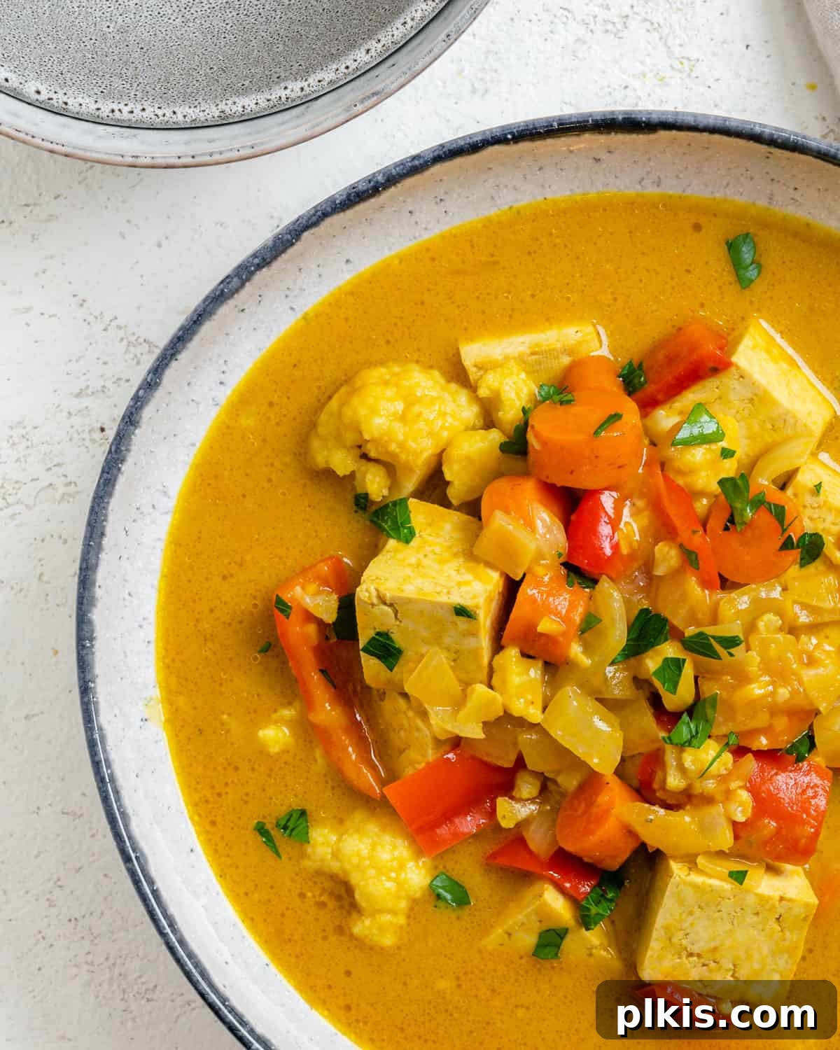 Golden Pumpkin Curry 2 A vibrant bowl of Pumpkin Curry against a light, inviting surface, garnished with fresh herbs.
