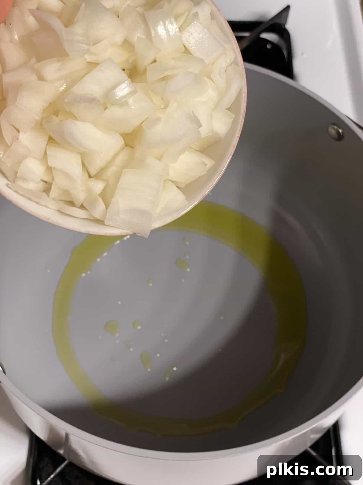 Golden Pumpkin Curry 4 A process shot showing diced onions being added to a hot pot with oil, ready to be sautéed.