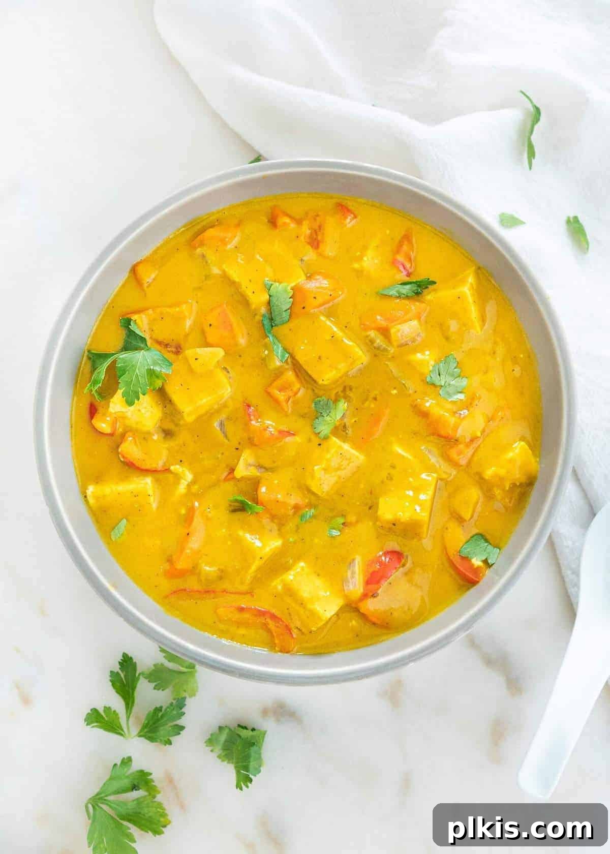Golden Pumpkin Curry 8 A beautifully arranged finished bowl of pumpkin curry, artfully placed against a pristine white marble background, ready to be enjoyed.