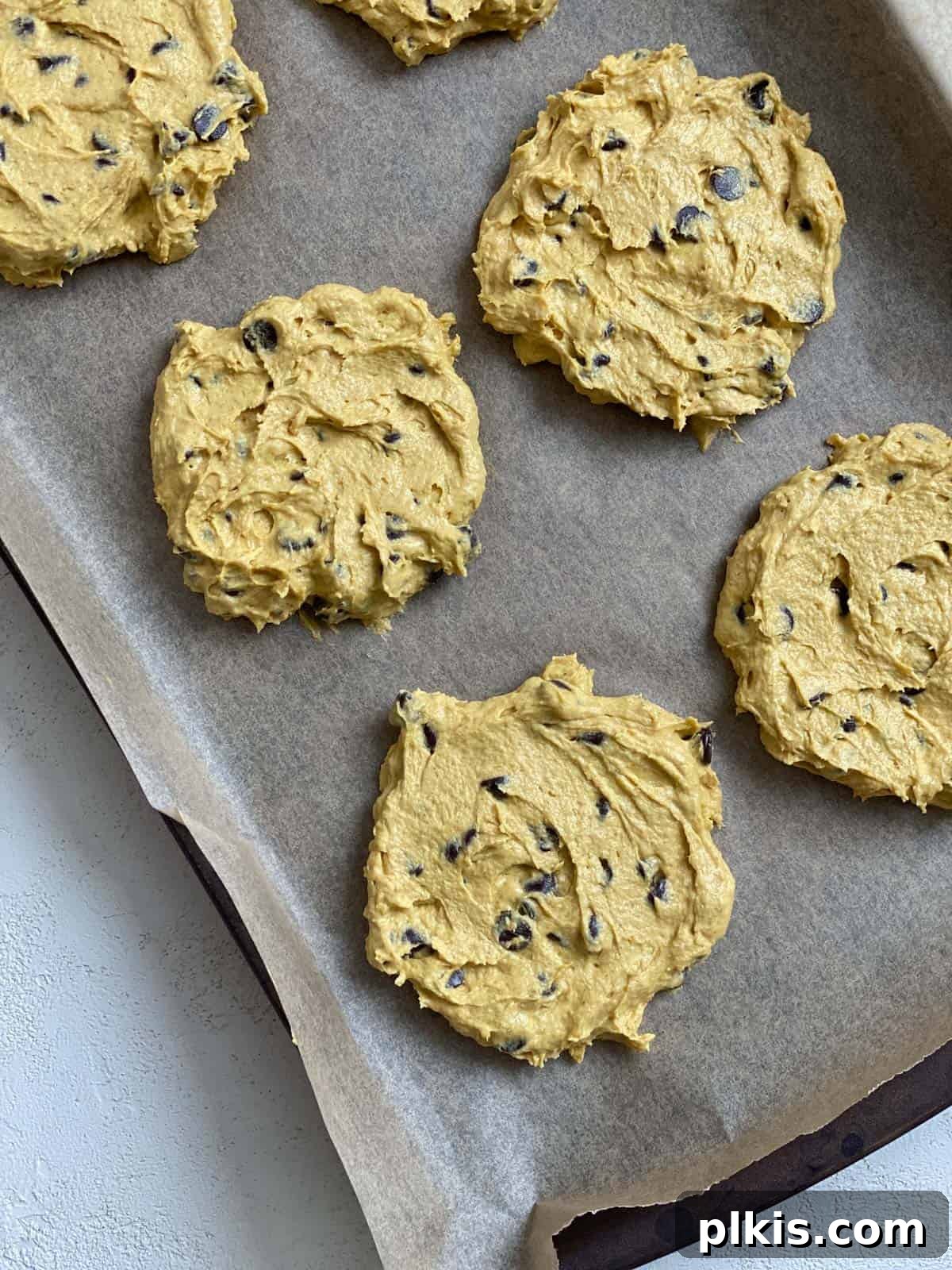 Harvest Spice Vegan Pumpkin Chocolate Chip Cookies 6 Unbaked Vegan Pumpkin Chocolate Chip Cookies on a cookie sheet