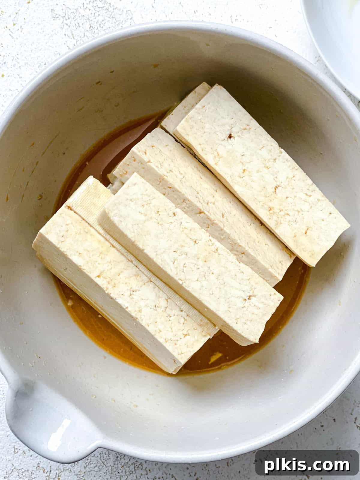 Island-Spiced Tofu with Coconut Lime Drizzle 4 Process shot showing tofu in a bowl with marinade.
