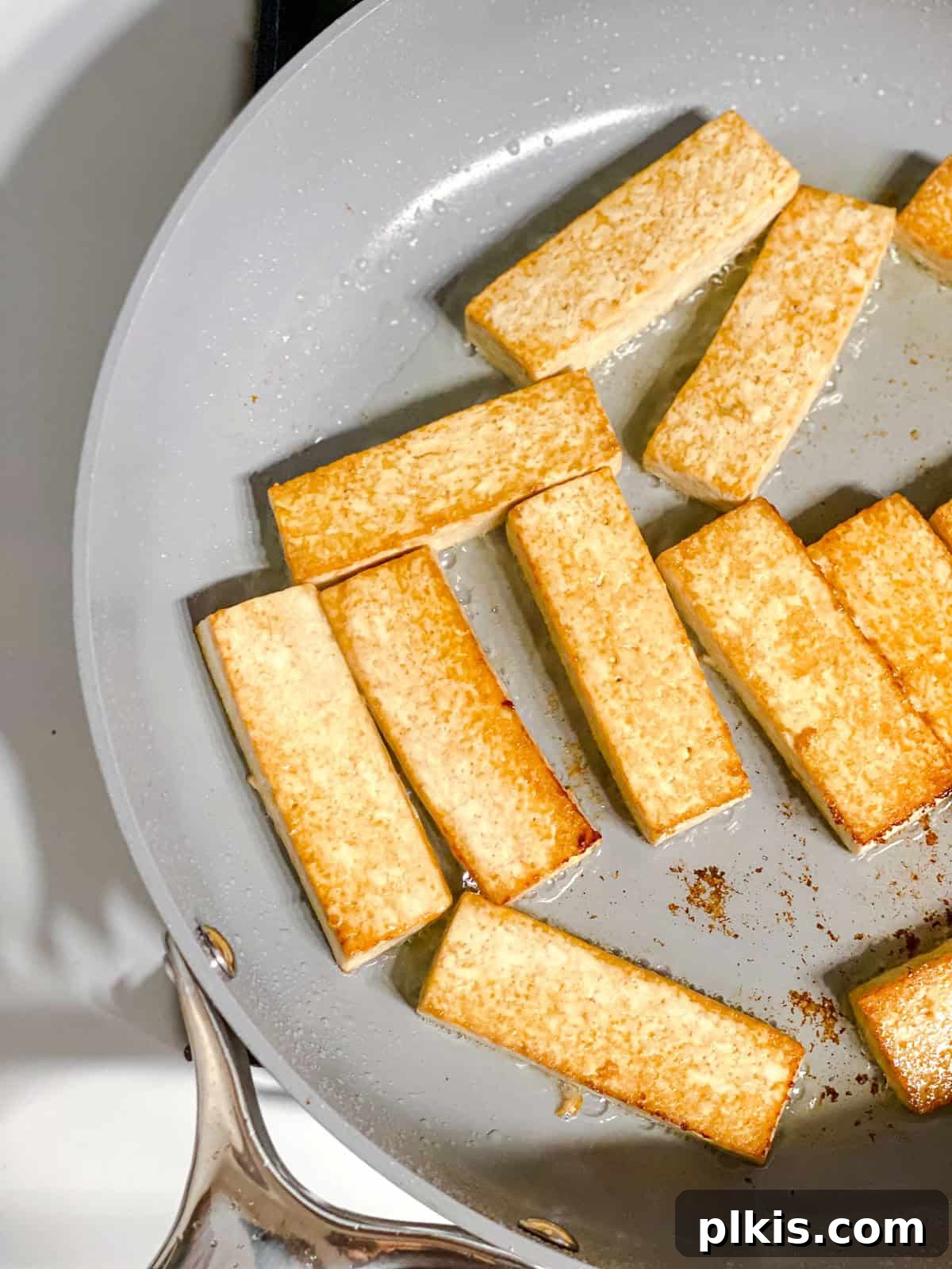 Island-Spiced Tofu with Coconut Lime Drizzle 5 Process shot showing tofu sizzling in a pan.