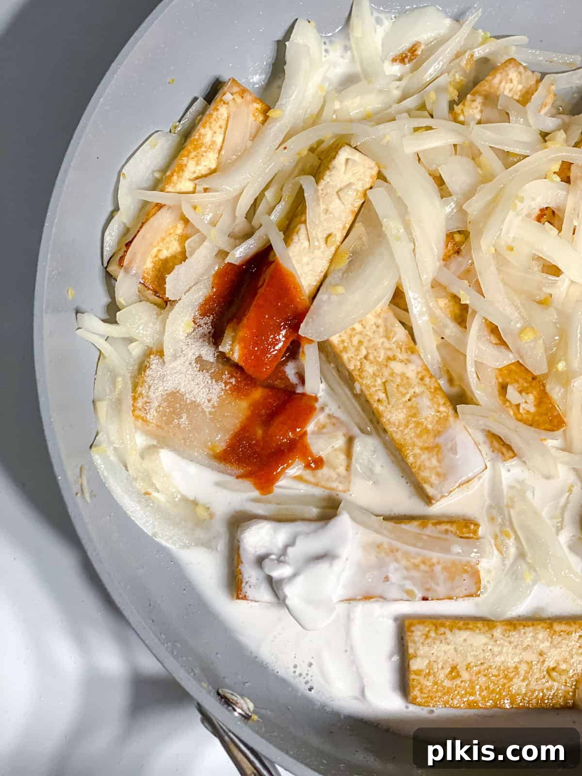 Island-Spiced Tofu with Coconut Lime Drizzle 7 Process shot showing tofu simmering in coconut lime sauce in a pan.