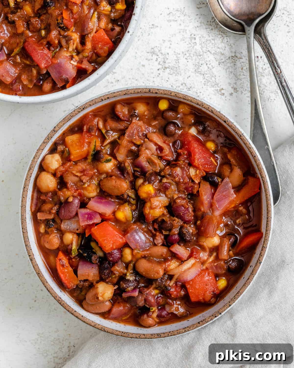 The Ultimate Vegan Bean Chili stovetop Slow Cooker Instant Pot 14 A vibrant bowl of completed Vegan Bean Chili, garnished with fresh cilantro and a dollop of vegan sour cream, beautifully presented against a light background.