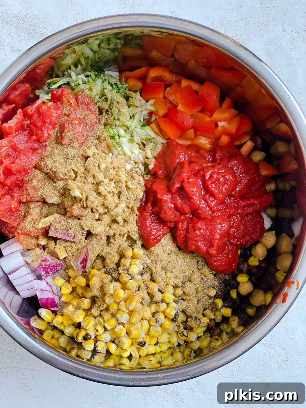 The Ultimate Vegan Bean Chili stovetop Slow Cooker Instant Pot 6 Overhead shot showing the process of mixing all chili ingredients together in a slow cooker pot with a wooden spoon.