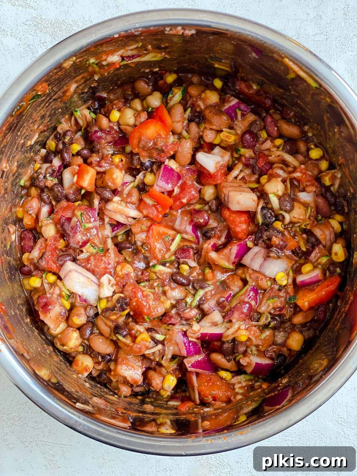The Ultimate Vegan Bean Chili stovetop Slow Cooker Instant Pot 7 Another process shot of chili ingredients being thoroughly mixed in a slow cooker, ensuring all components are well combined.