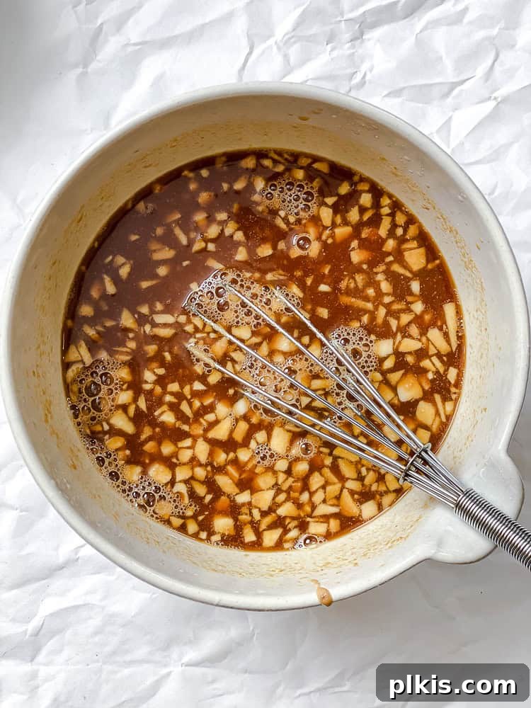 Process shot showing a creamy peanut sauce being stirred in a small mixing bowl.