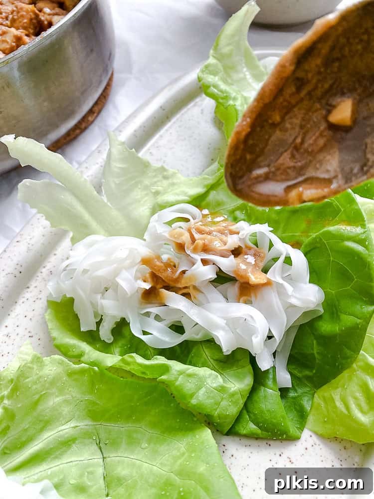 Process shot showing assembled Tofu Lettuce Wraps with noodles and tofu on lettuce leaves.