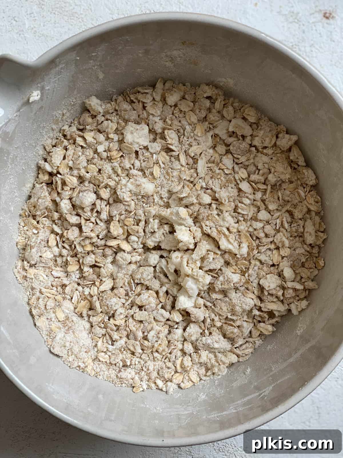 Autumn Apple Cranberry Delight 6 A bowl containing a mixture of rolled oats, flour, and sugar, blended into pebble-sized pieces, representing the prepared crisp topping.