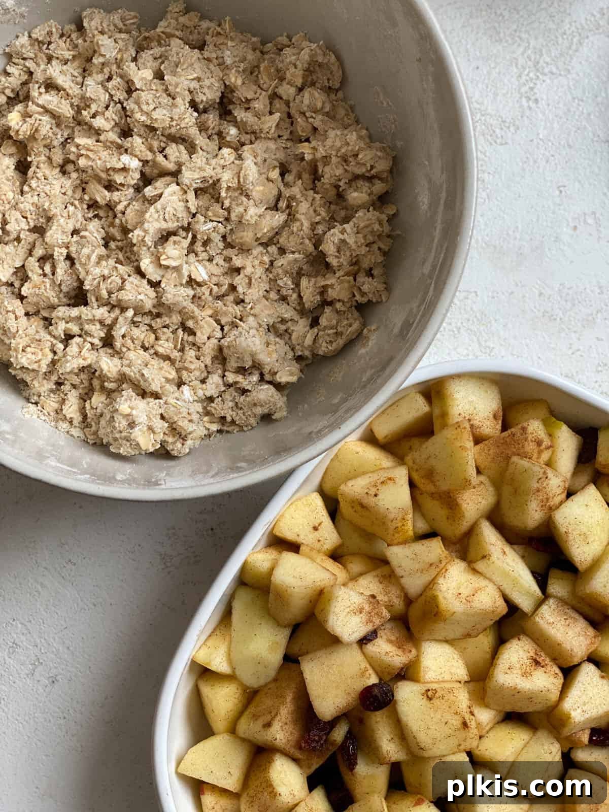 Autumn Apple Cranberry Delight 10 Two individual bowls presented on a white surface: one containing the mixed apple and cranberry filling, and the other holding the prepared oat and flour crisp topping, ready for assembly.