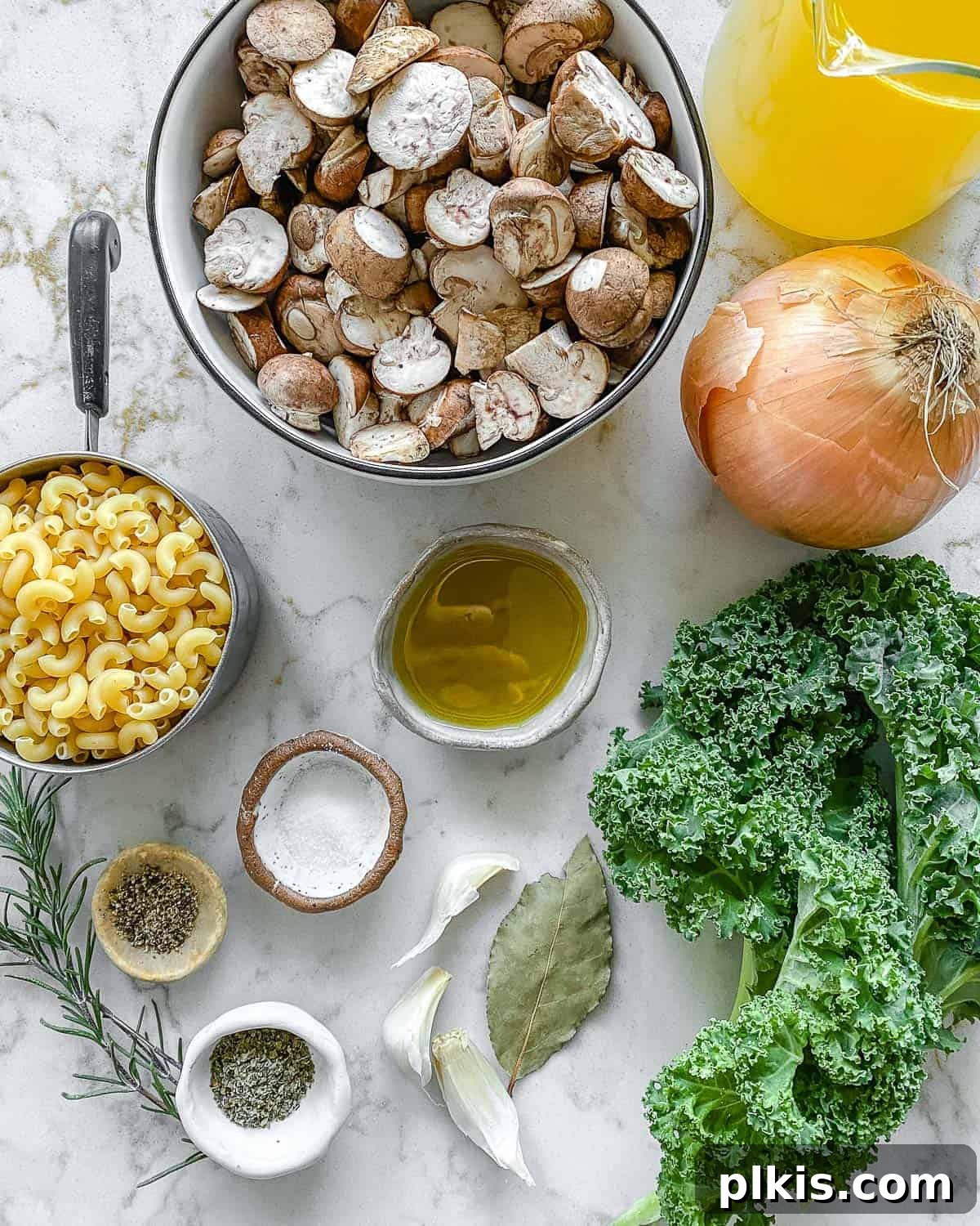 Velvet Mushroom Elixir 3 A collection of fresh ingredients laid out, including sliced mushrooms, diced onions, minced garlic, a bay leaf, dried herbs, and a bowl of orzo, all ready for making mushroom orzo soup.