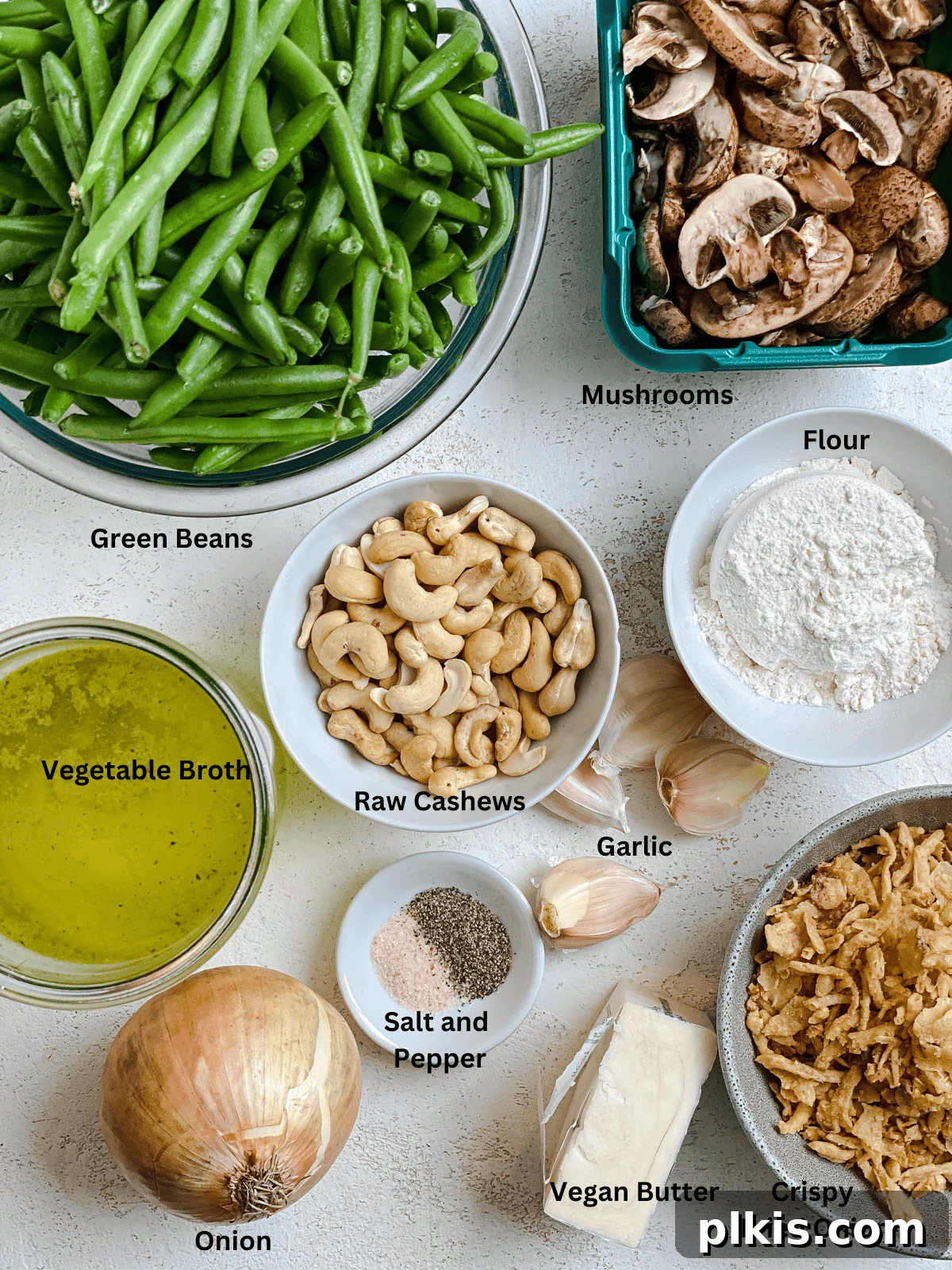 Plant-Powered Green Bean Casserole 3 All the fresh ingredients for Dairy-Free Green Bean Casserole laid out on a clean white surface, including green beans, mushrooms, onions, cashews, and vegetable broth.