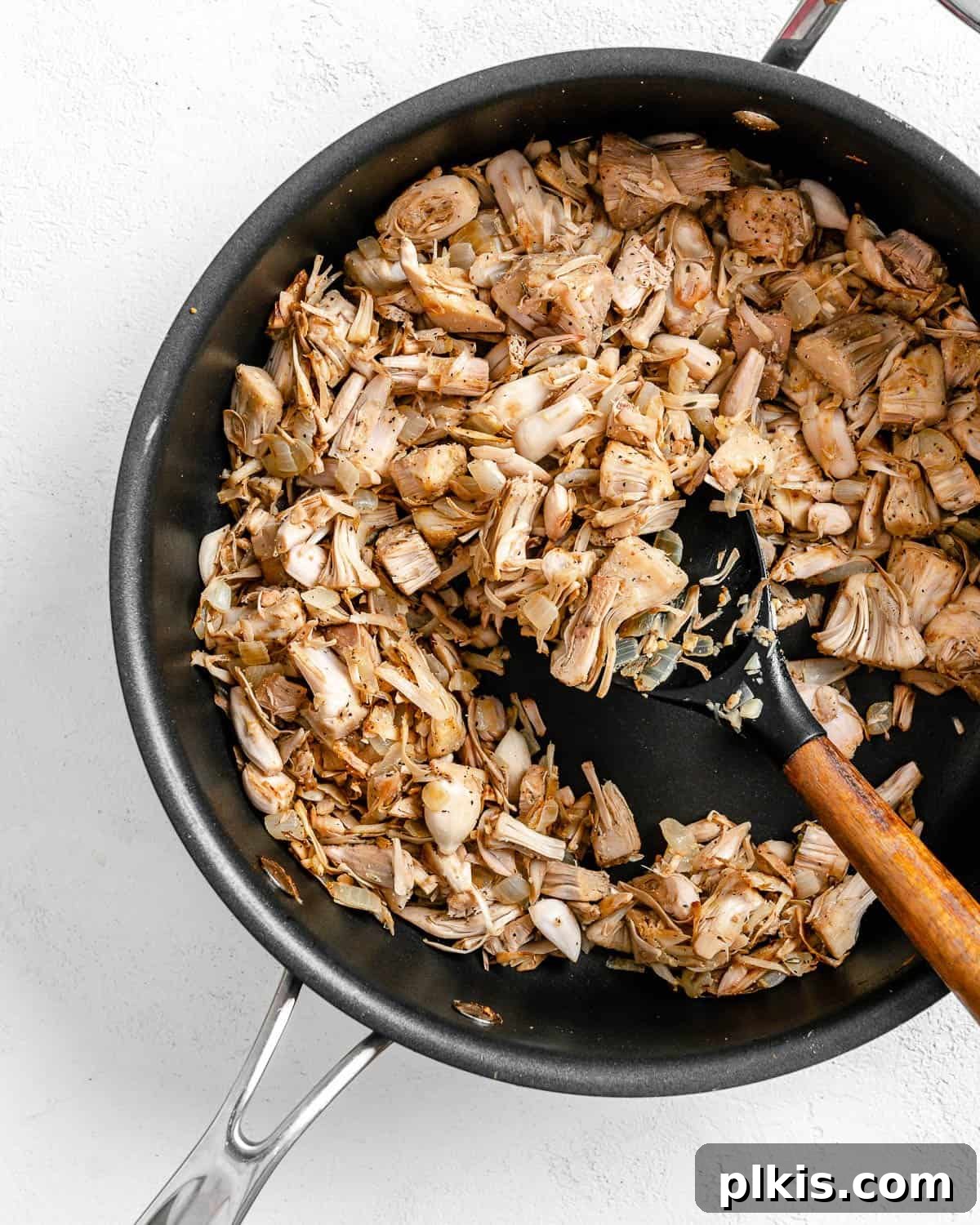 Smoky Vegan Jackfruit BBQ 11 process of mixing jackfruit and spices in a black pan against white background