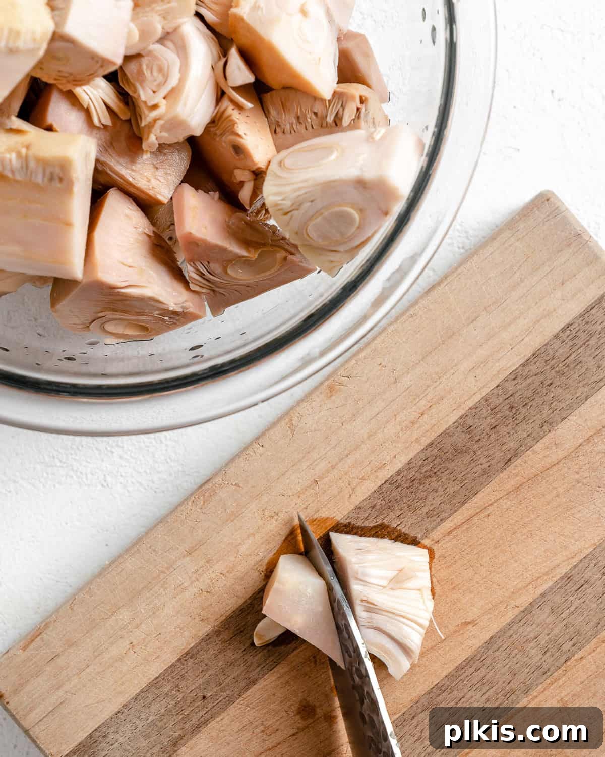 Smoky Vegan Jackfruit BBQ 4 bowl of jackfruit alongside cutting board with the process of cutting a piece of jackfruit