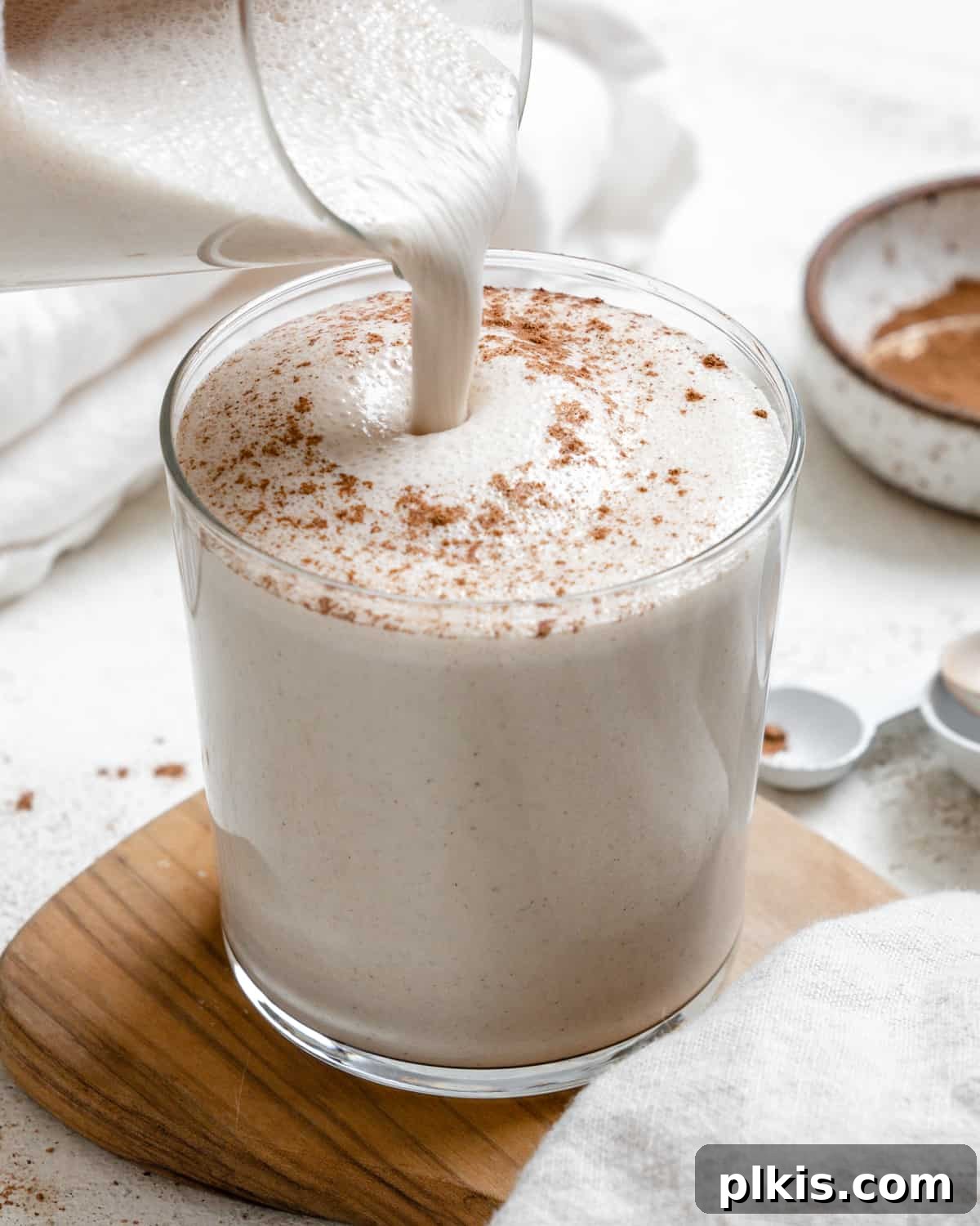 Effortless Dairy-Free Eggnog 7 A close-up shot of a garnished glass of Easy Vegan Eggnog, with a subtly blurred background, emphasizing its creamy texture and festive appeal.