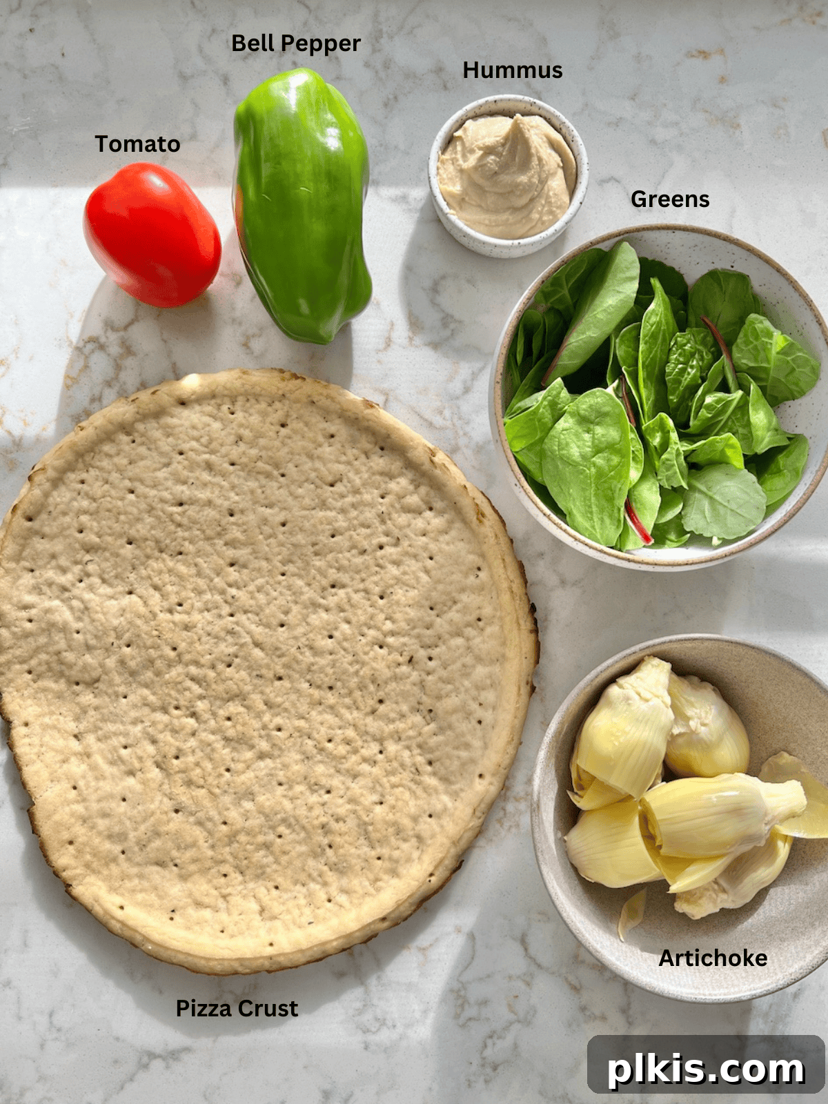 Mediterranean Hummus Pizza: Dairy-Free and Your Way 3 Ingredients for hummus pizza measured out on a white surface, including bell peppers, tomatoes, spinach, and a bowl of hummus.