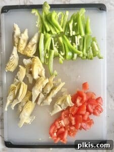 Mediterranean Hummus Pizza: Dairy-Free and Your Way 4 Hummus pizza ingredients cut up on a cutting board, ready for assembly.