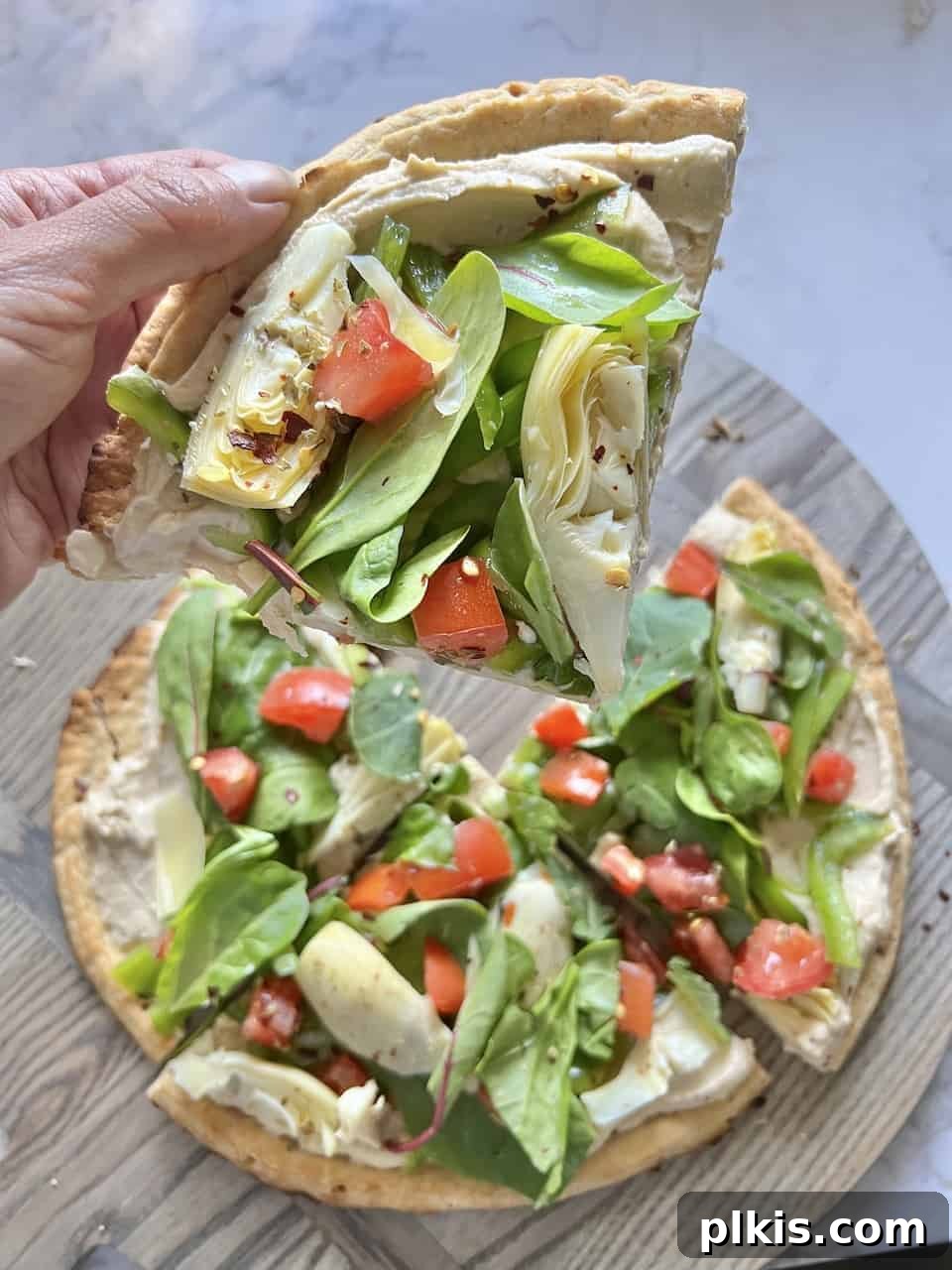 Mediterranean Hummus Pizza: Dairy-Free and Your Way 5 Close up of a completed hummus pizza with another pizza in the background, ready to be served.