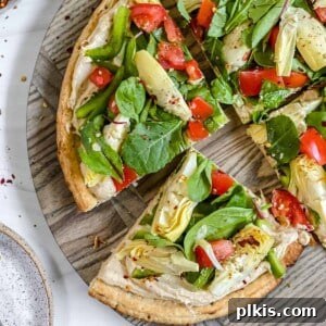 Mediterranean Hummus Pizza: Dairy-Free and Your Way 7 Finished hummus pizza sliced on a gray surface, garnished with fresh herbs.