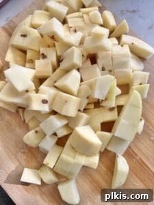 Cut up potatoes on a brown cutting board, ready for boiling.