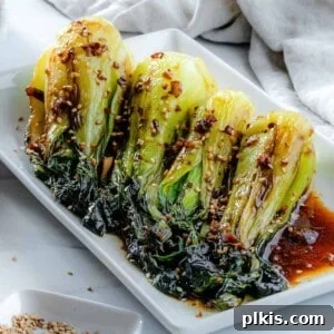 completed baby bok choy with soy sauce and garlic on a white serving tray against a white background