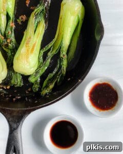 Garlic Soy Glazed Baby Bok Choy 7 A vibrant stir-fry of baby bok choy in a skillet, with measured soy sauce and mushroom sauce ready to be added, ensuring perfect flavor.