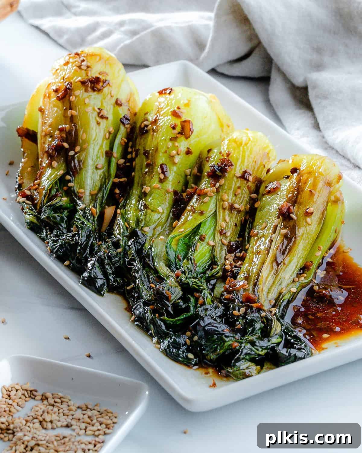 Garlic Soy Glazed Baby Bok Choy 8 The finished dish: perfectly stir-fried baby bok choy with soy sauce and garlic, artfully arranged on a white serving tray, garnished with sesame seeds.