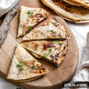a vegan bean quesadilla sliced into fours on a wooden board.