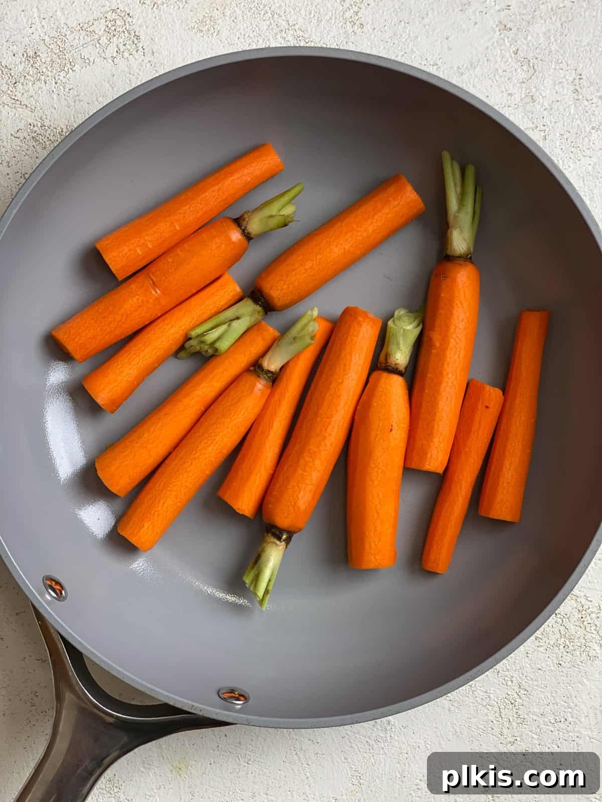 Mastering Glazed Carrots and Their Delicious Flavor Variations 5 Process shot showing carrots and glaze ingredients starting to cook in a large skillet over medium-high heat on a stovetop.