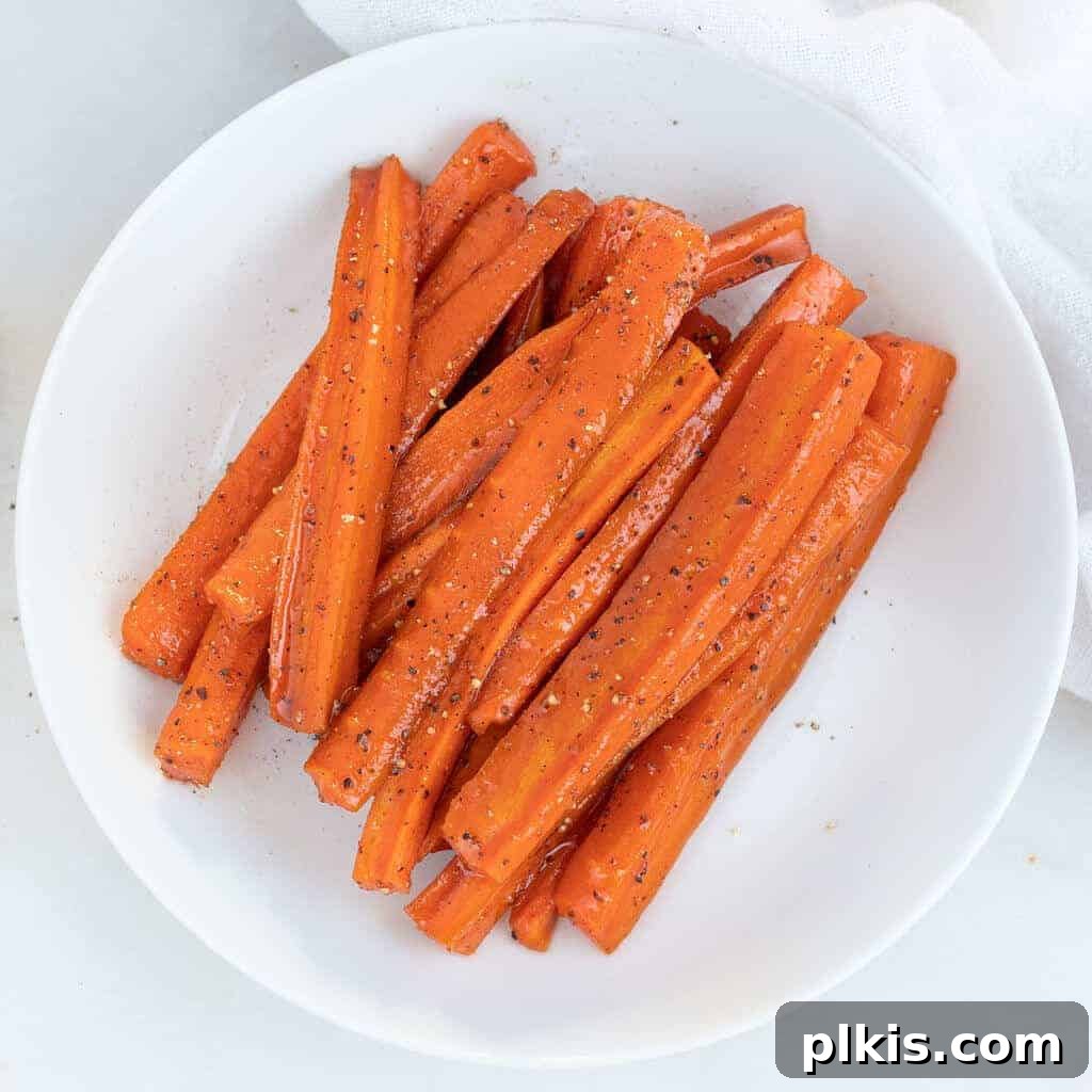 Mastering Glazed Carrots and Their Delicious Flavor Variations 9 A serving of perfectly glazed carrots on a white plate, set against a pristine white background, showcasing their appetizing shine and tender texture.