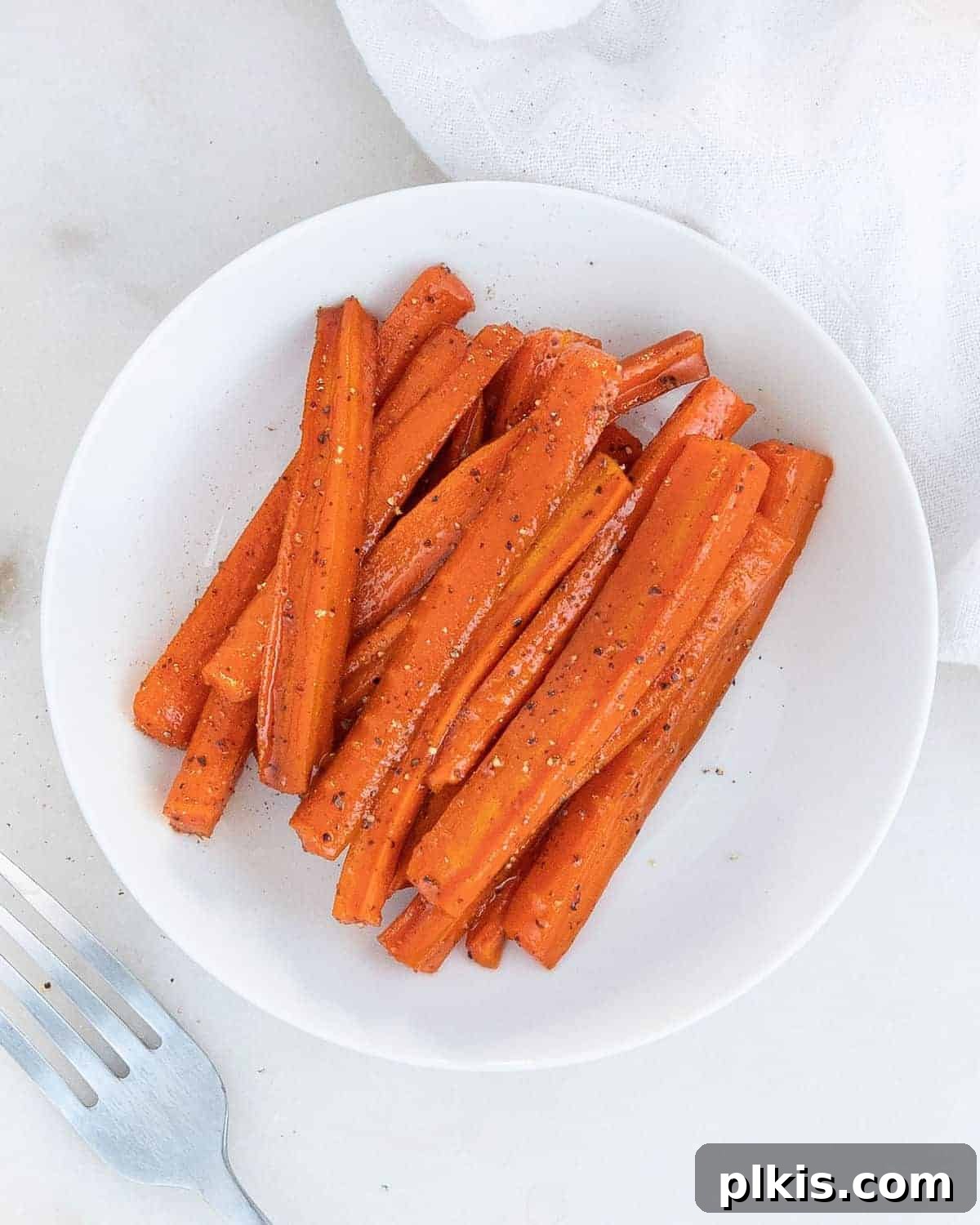 Mastering Glazed Carrots and Their Delicious Flavor Variations 10 A close-up of glazed carrots on a white plate, highlighting their glossy coating and the vibrant orange color, ready for serving.