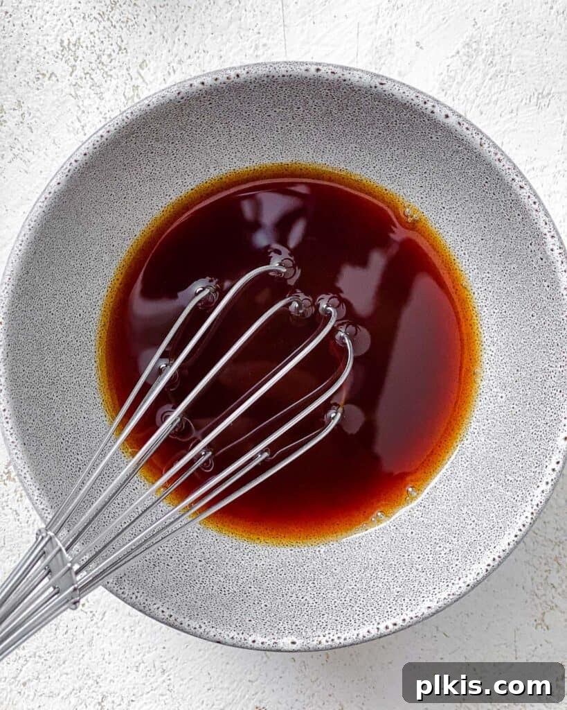 Golden Sautéed Eggplant with Maple Soy Glaze 6 Process shot of mixing sauce in a white bowl with whisk