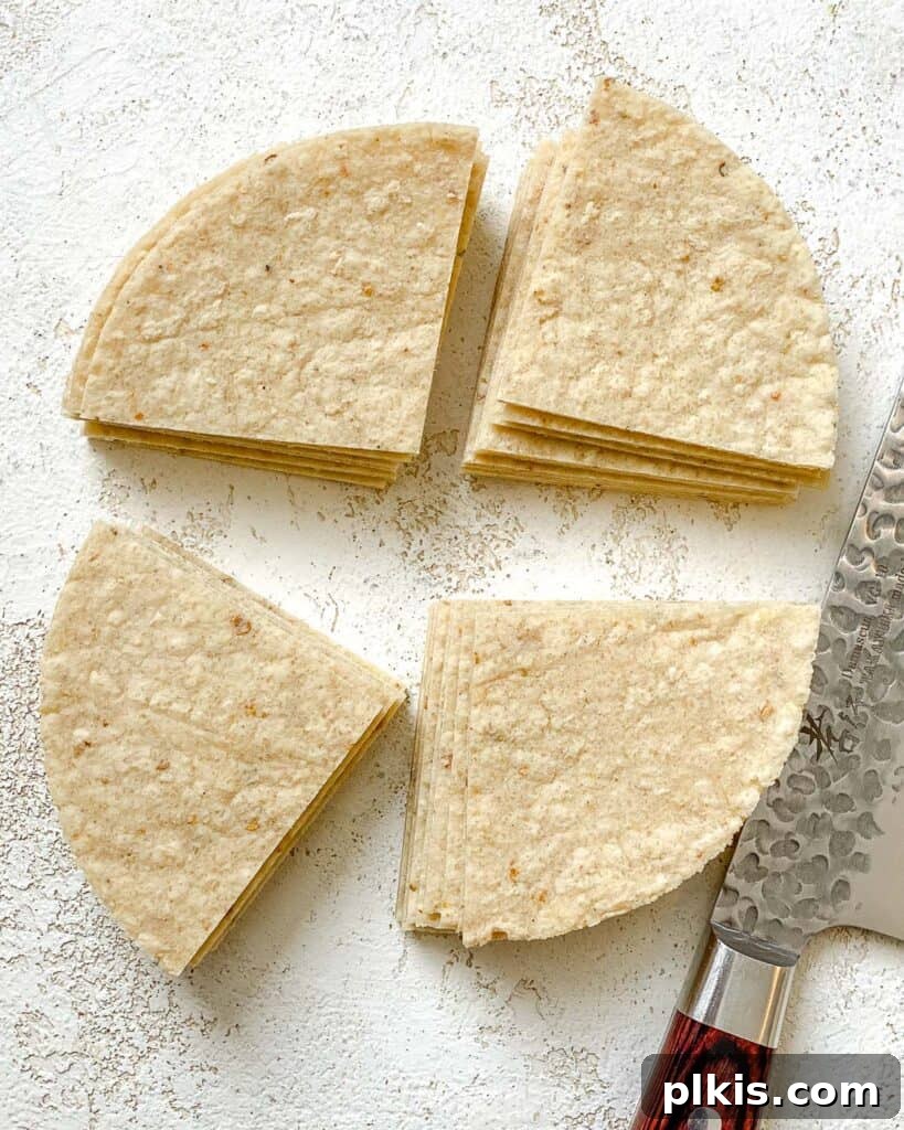 The Crispiest Air Fryer Tortilla Chips 5 corn tortilla sliced into quarters against a white surface