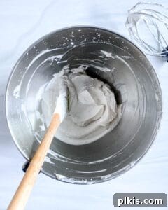 process of vegan whipped cream being mixed in a stainless steel bowl with a hand mixer
