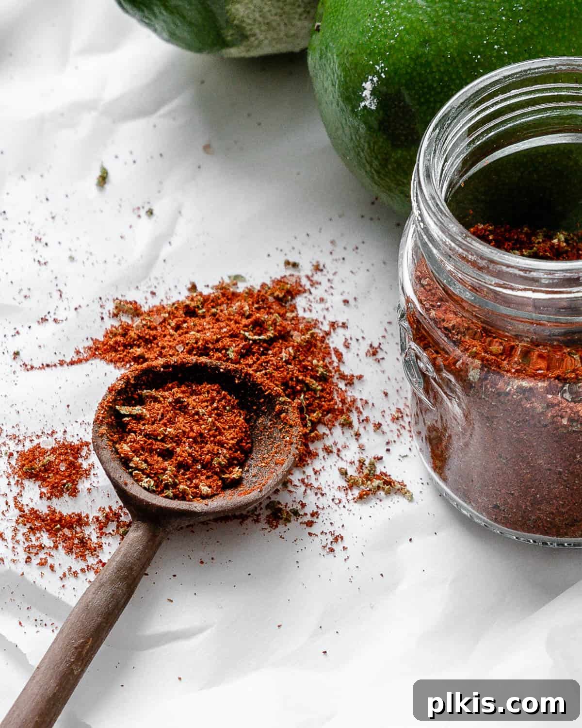 Make Your Own Tangy Chili Lime Dust 2 A close-up of vibrant homemade Chili Lime Seasoning (Tajin) in a small glass jar, set against a clean white background. The bright red-orange hue of the seasoning is clearly visible, highlighting its zesty and spicy appeal. The image is crisp, focusing on the texture and color of the spice blend, making it look incredibly appetizing and ready to use.