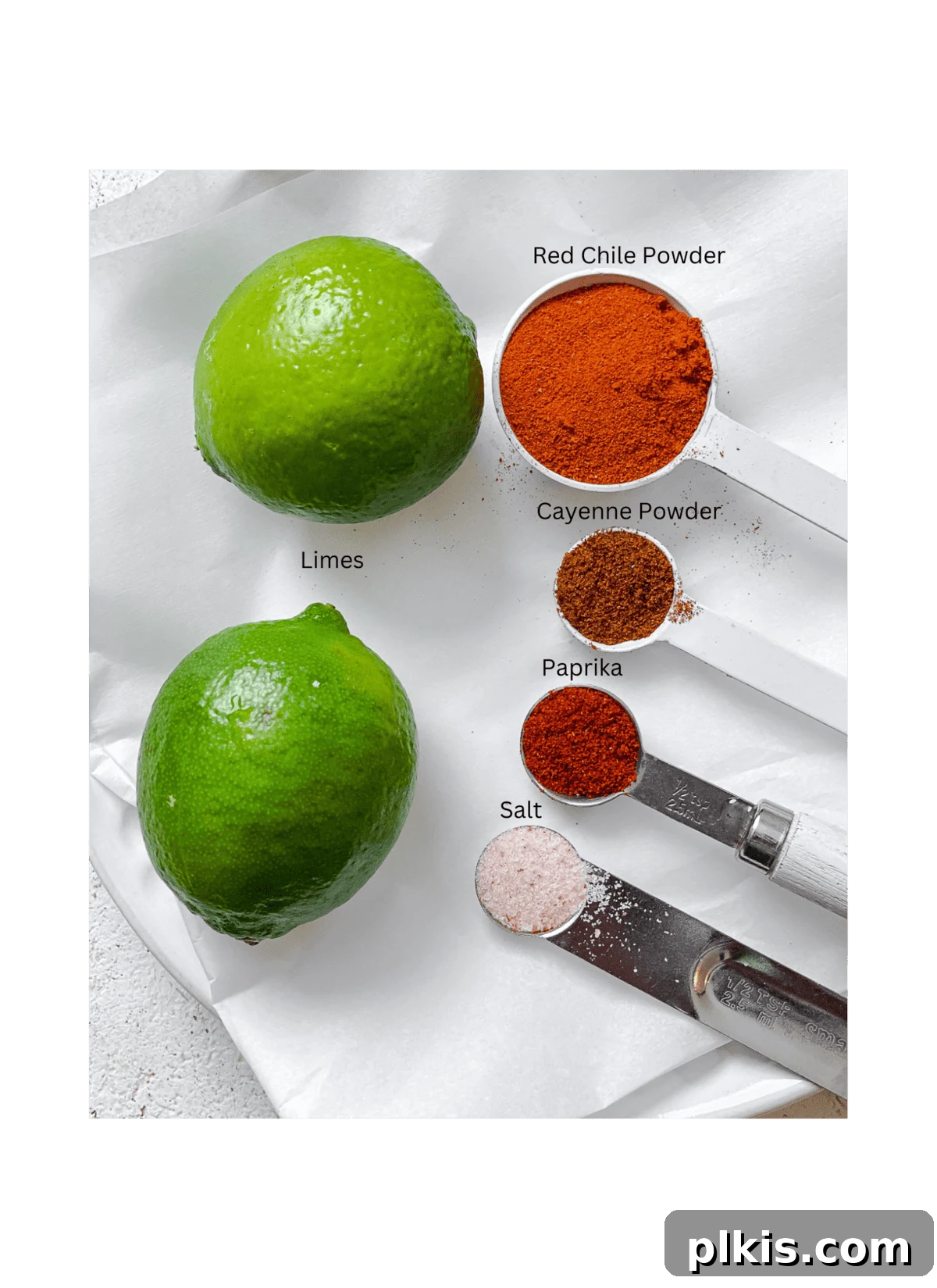 Make Your Own Tangy Chili Lime Dust 3 Individual ingredients for Homemade Chili Lime Seasoning (Tajin) carefully measured out into small bowls and arranged on a white surface. The vibrant green of lime zest, the rich red hues of various chile powders, and glistening salt crystals are all clearly visible, showcasing the fresh, high-quality components used in the blend.