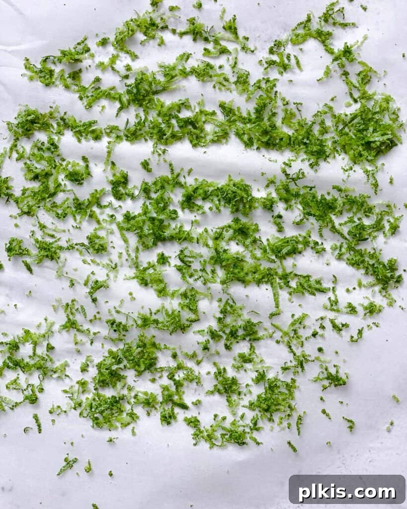 Make Your Own Tangy Chili Lime Dust 5 Freshly grated lime zest spread evenly on a sheet of parchment paper laid on a flat surface, beginning the drying process. The zest is bright green and delicate.