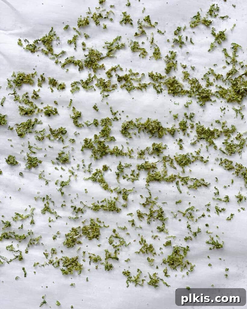 Make Your Own Tangy Chili Lime Dust 6 Another view of lime zest drying on parchment paper, showing a slightly more dried texture. The zest maintains its vibrant green color but has begun to shrink, indicating moisture loss.