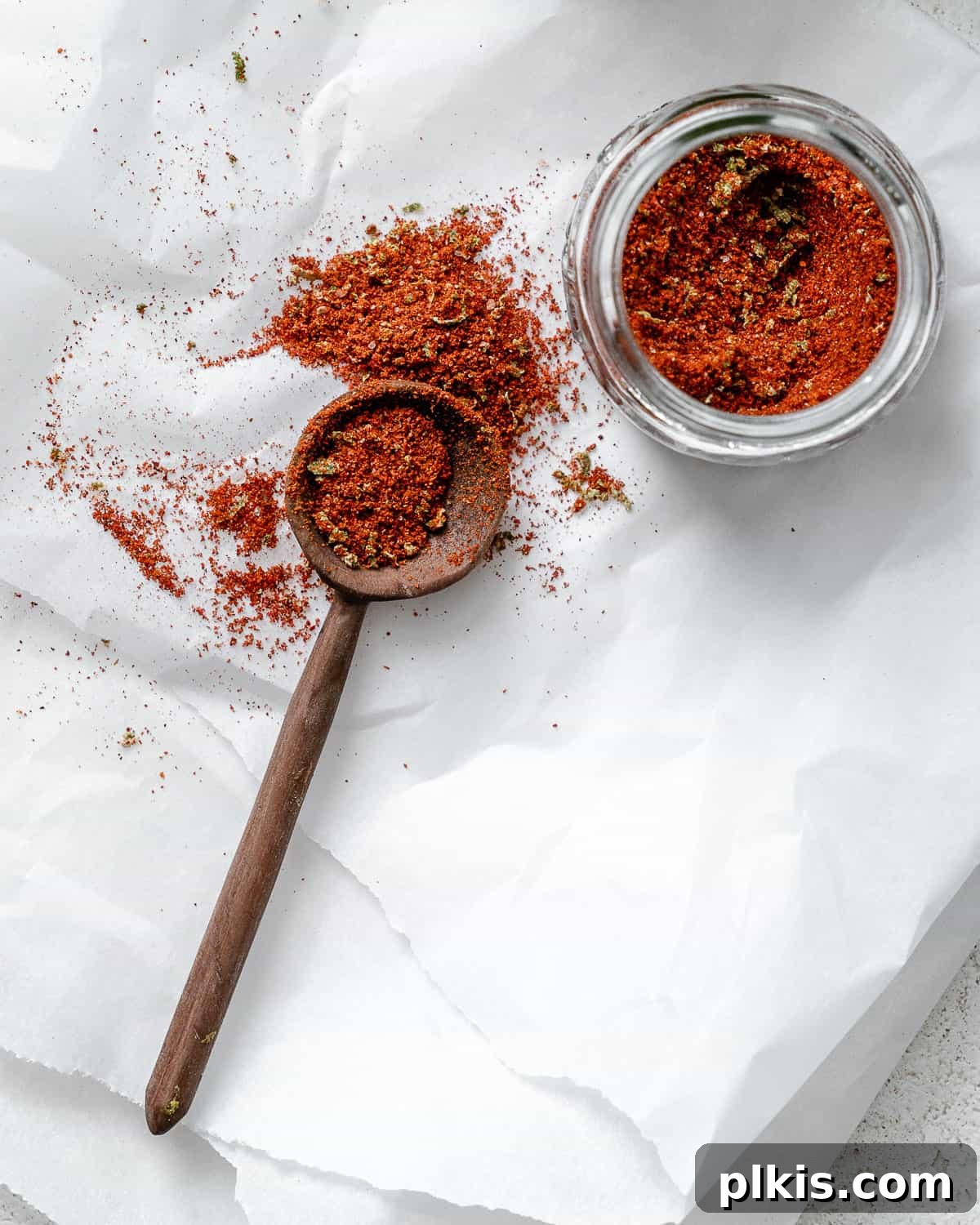 Make Your Own Tangy Chili Lime Dust 8 A small glass jar filled with vibrant homemade Chili Lime Seasoning (Tajin) is prominently displayed on a simple white surface. The seasoning's rich color and fine texture are showcased, inviting viewers to experience its zesty and spicy flavors. The jar is sealed, implying freshness and readiness for use.