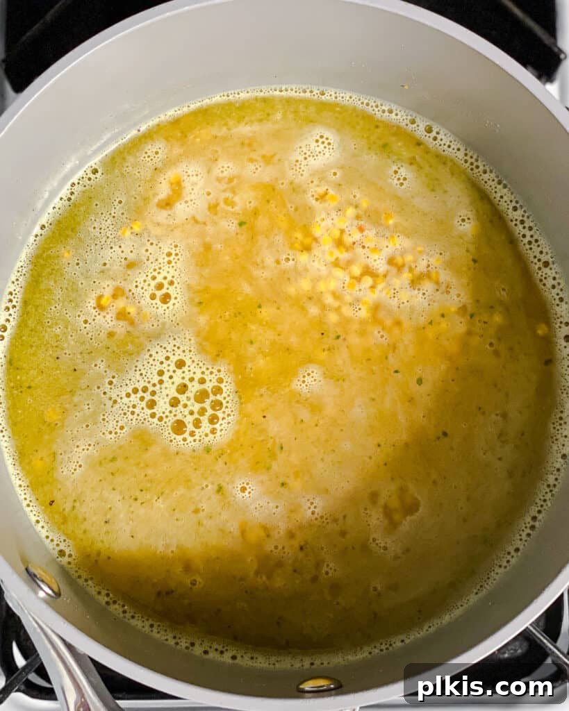 Roasted Garden Couscous Medley 6 Process shot of couscous simmering in a covered pot on the stovetop.