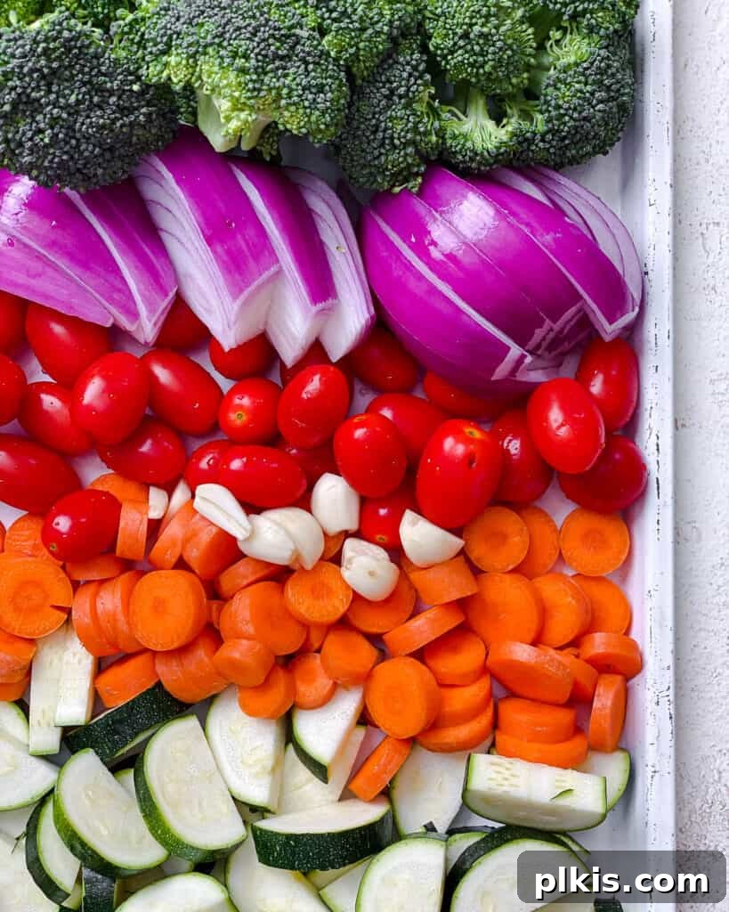Roasted Garden Couscous Medley 7 A cutting board with various chopped vegetables, including broccoli, zucchini, carrots, and red onion, prepared for roasting.